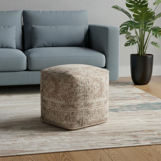 Patterned ottoman in front of a gray sofa with a plant in the background