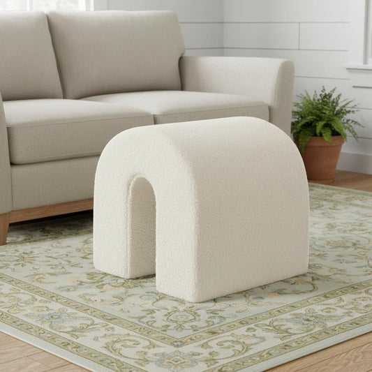 Beige ottoman in a living room setting with a beige sofa and green patterned rug.
