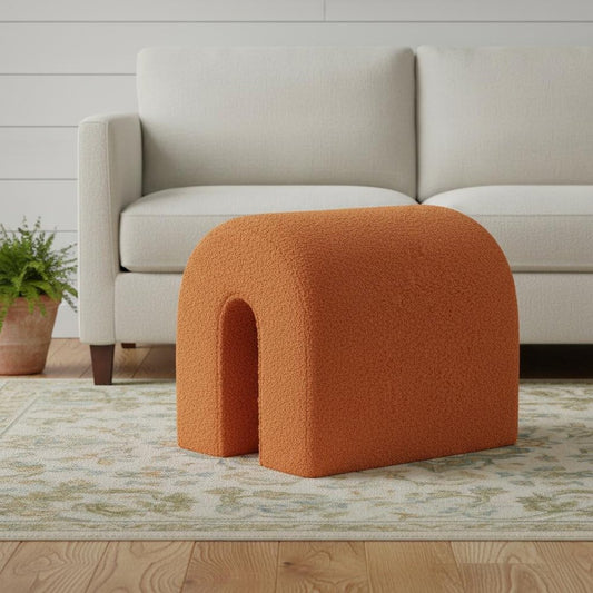 Orange textured ottoman in a living room setting with a beige sofa and wooden floor.