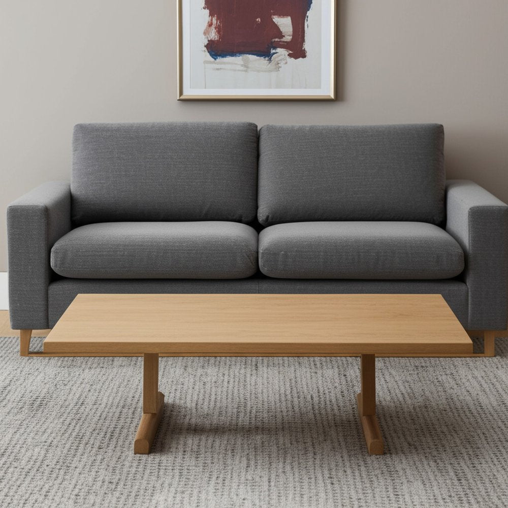 Gray sofa with a wooden coffee table in a room with a painting on the wall.